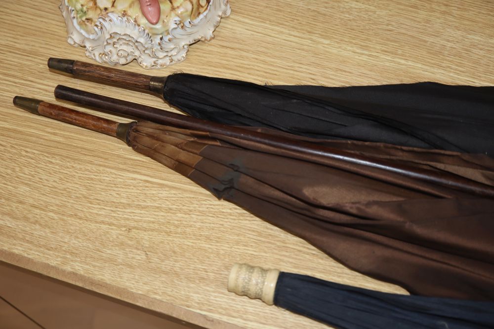 Three parasols, one with a carved ivory handle, and a hardwood walking cane